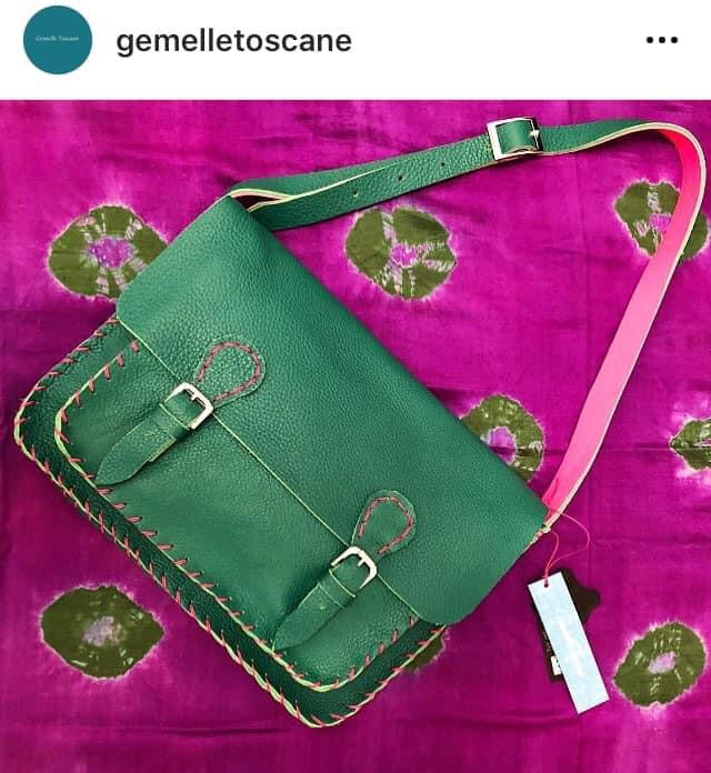 Cartella artigianale in pelle verde con dettagli cuciti a mano su sfondo viola con motivi floreali