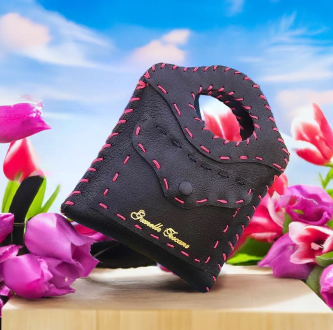 Piccola borsa artigianale con cuciture rosa in tracolle in pelle artigianali su sfondo floreale