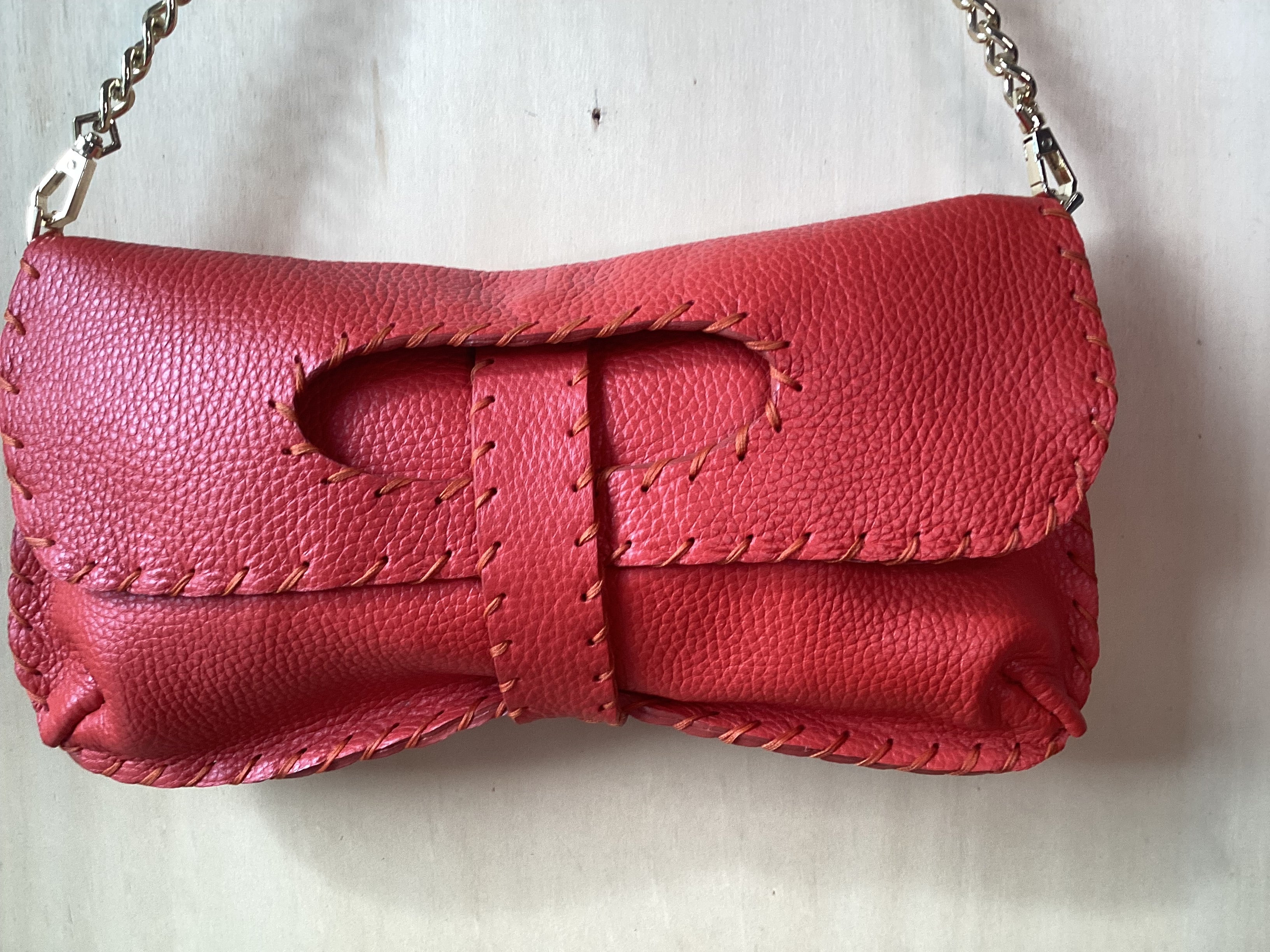 Pochette in pelle artigianale rossa con cuciture a vista e chiusura decorativa con catena metallica