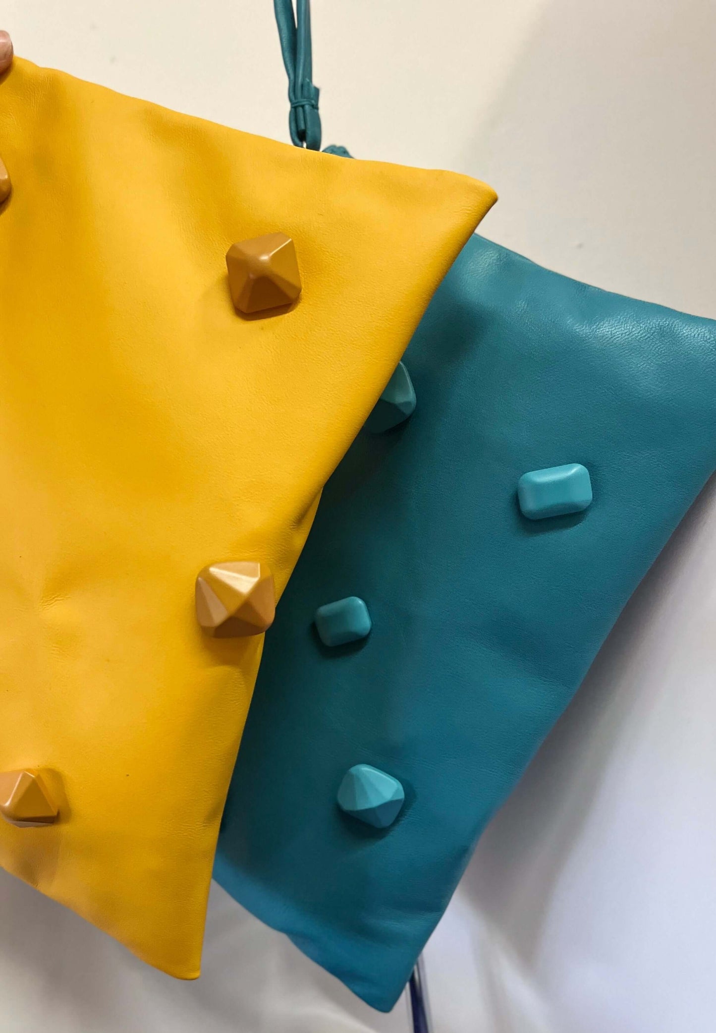 Pochette artigianale in pelle turchese con applicazioni effetto pietra.Turquoise clutch bag in nappa leather with matching stone effect applications.