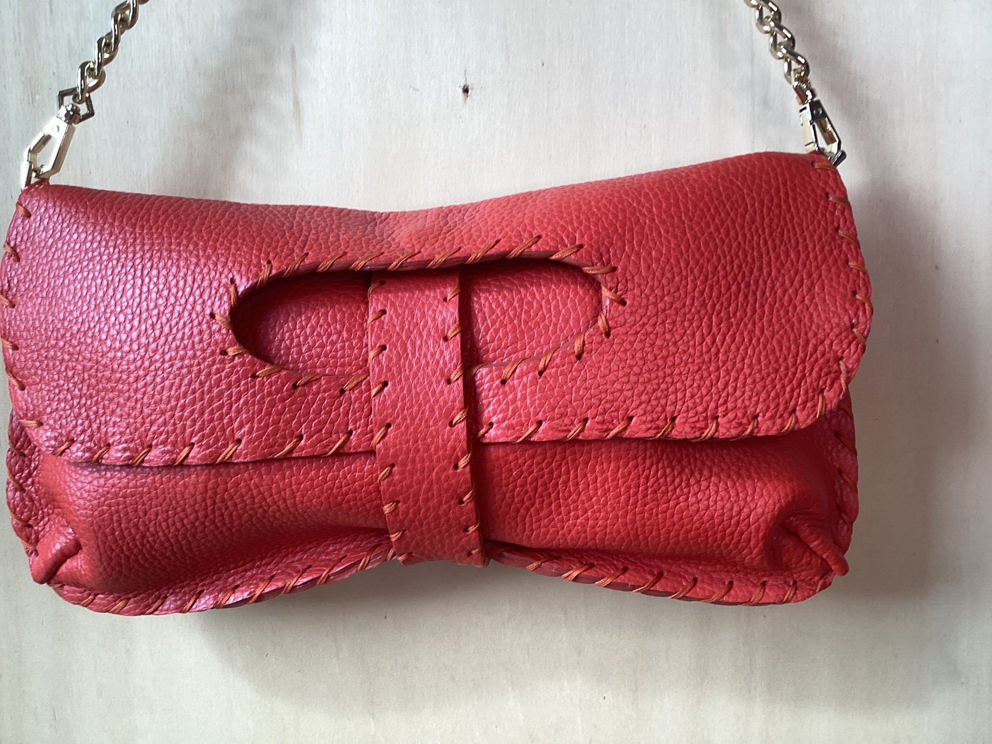 Borsa artigianale in pelle color coccio con finiture cucite a mano e tracolla a catena