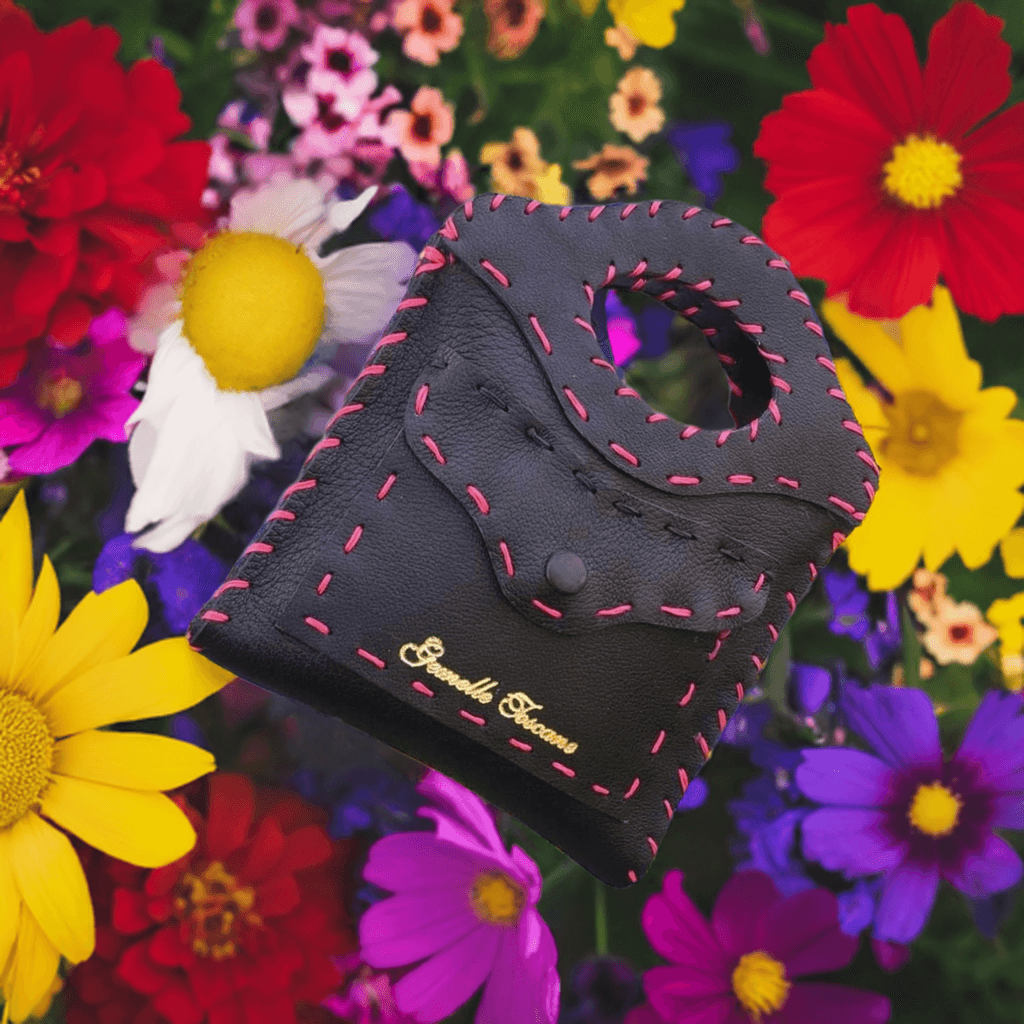 Borsa artigianale in pelle nera di Gemelle Toscane con dettagli cuciti a mano su uno sfondo floreale