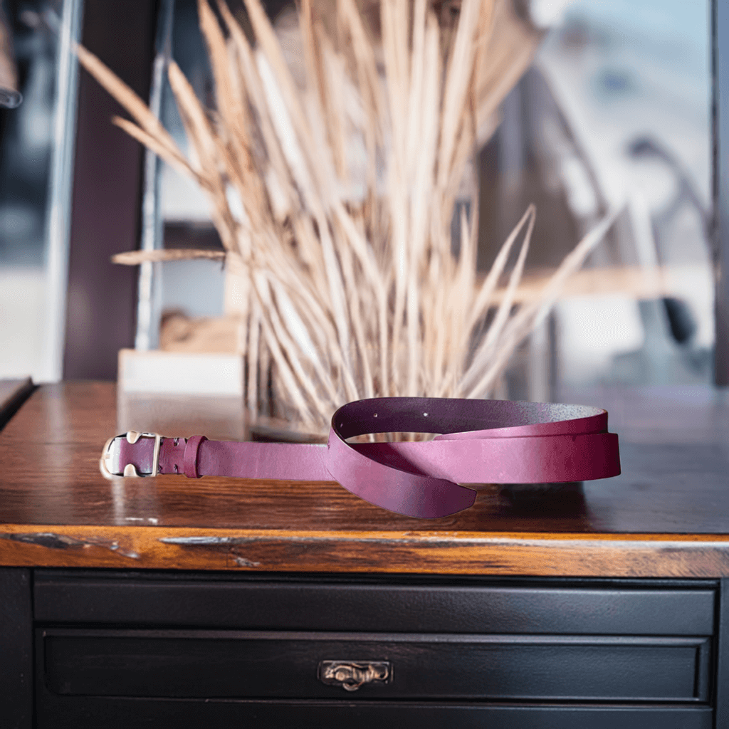 Cintura in cuoio bordeaux di Gemelle Toscane su un tavolo in legno con decorazioni naturali