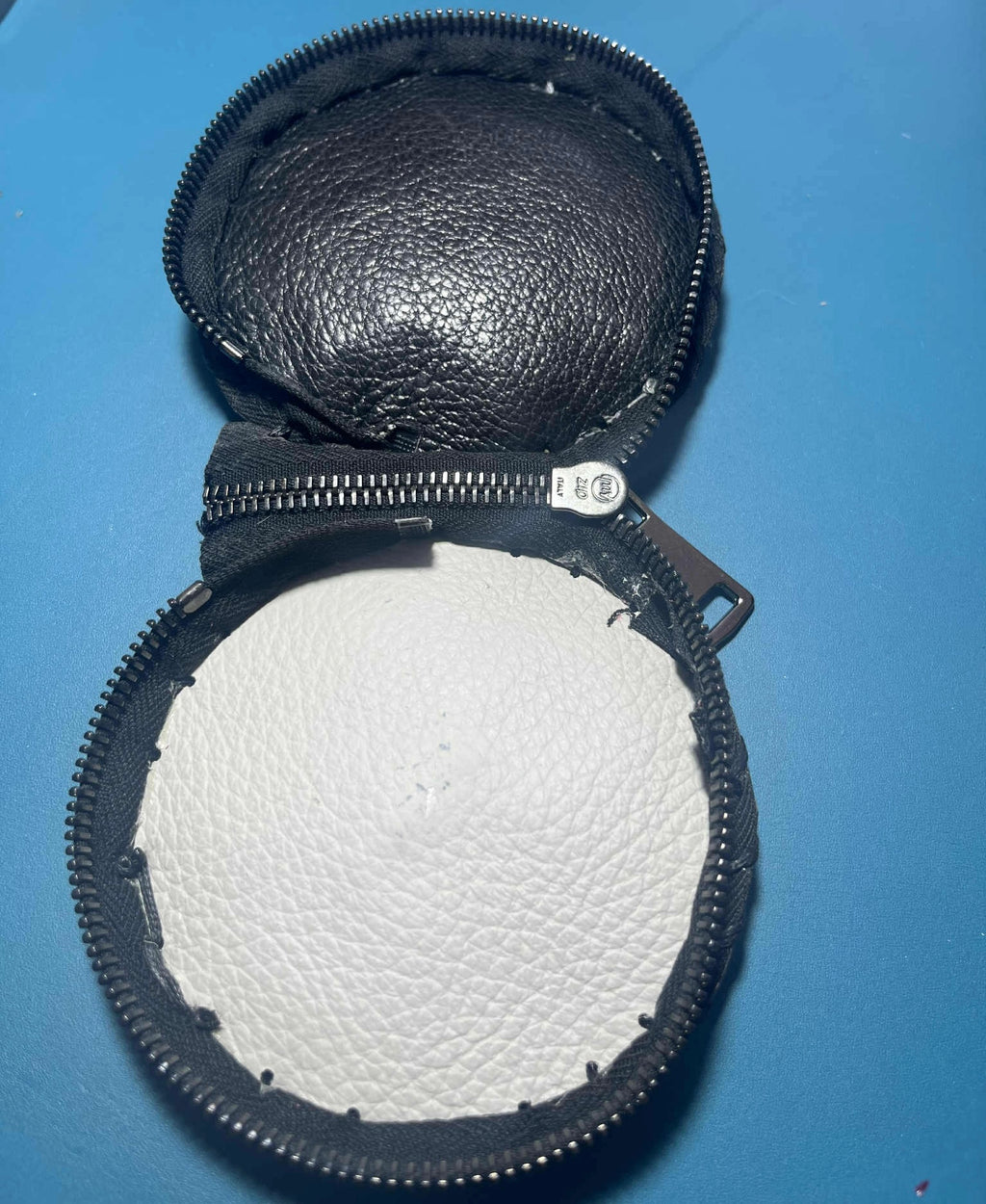 Portamonete artigianale in pelle nera con stampa pitone aperto su sfondo blu di Gemelle Toscane borse artigianali
